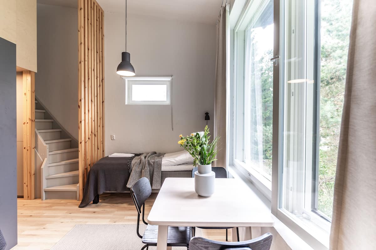 En modern inredning med en trappa, en säng, en matplats och ett stort fönster.