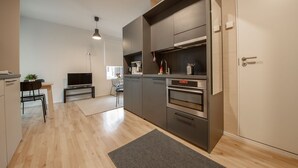 Una cucina moderna con elettrodomestici integrati, un'area pranzo con tavolo e sedie, e un'ampia finestra che offre luce naturale.