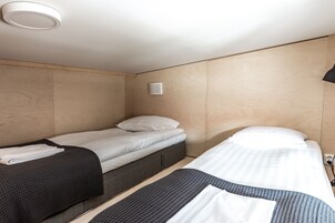 Una habitación de hotel con dos camas, una lámpara de techo y un respiradero en la pared.