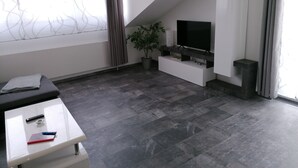 A modern living room with a flat-screen TV, a potted plant, and a white entertainment unit. - Stollis FeWo (Bensheim)