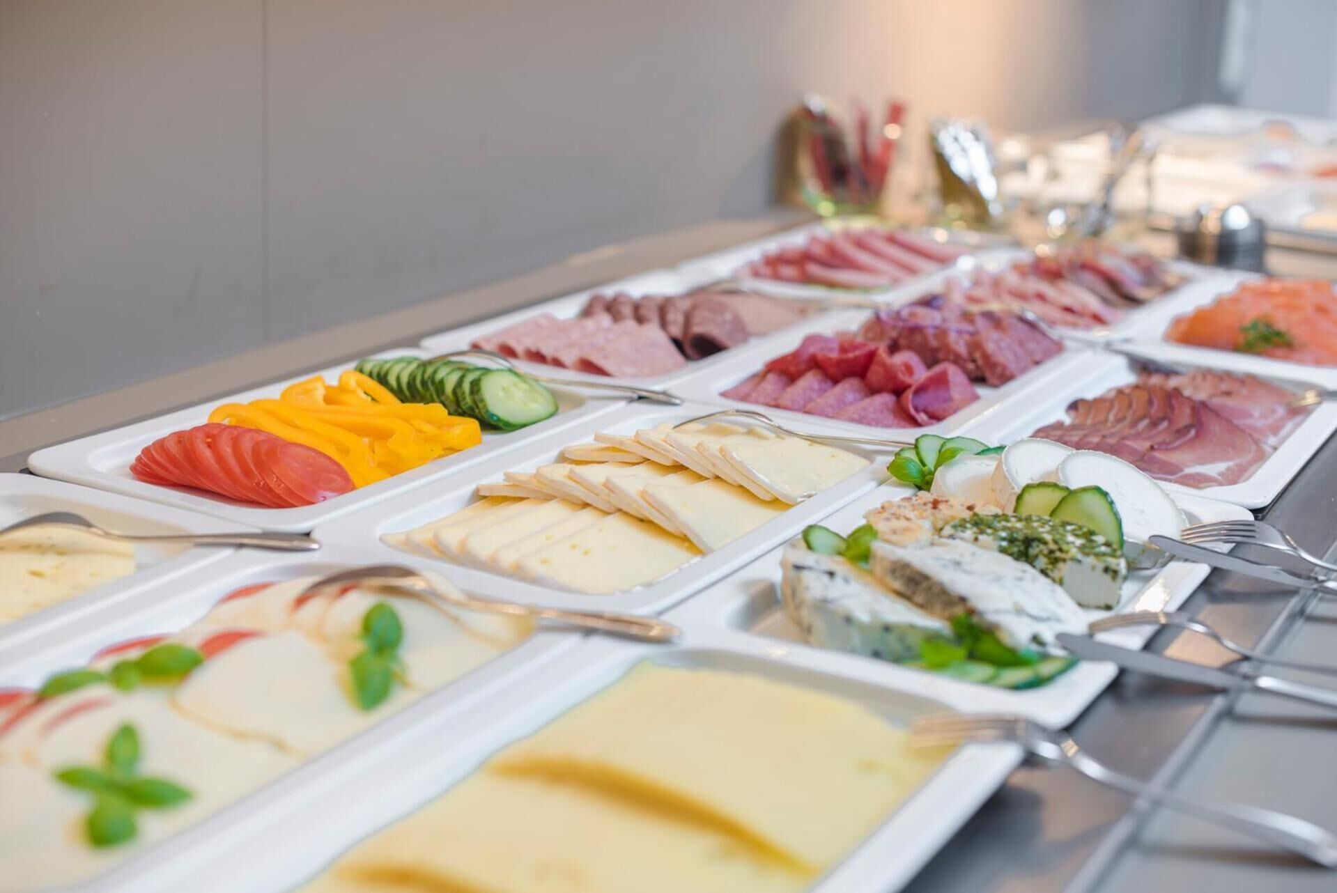 A buffet with various food items including meats, cheeses, and vegetables.