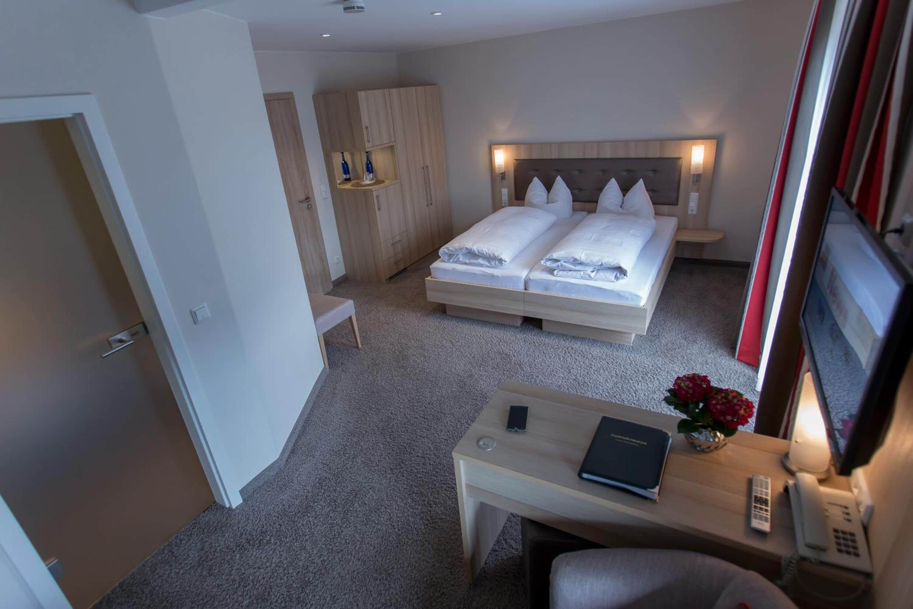 Ett hotellrum med en säng, sängbord, ett skrivbord och en tv.