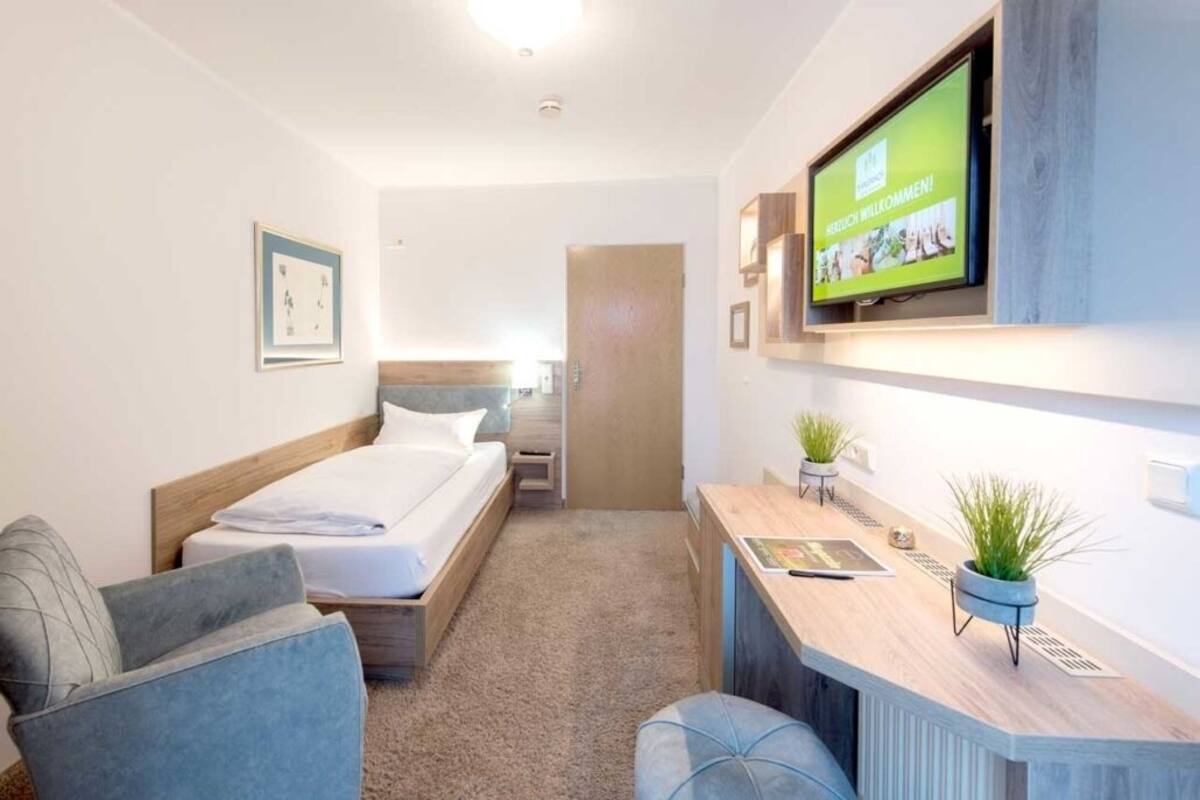 Ein modernes Hotelzimmer mit einem Bett, einem Schreibtisch mit Flachbildfernseher, einer Couch und einer kleinen Sitzecke.