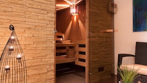 Ein modernes Interieur mit Steinwand, Glastisch mit Kerzen und einer Holzbänkl.