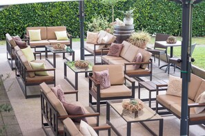 An outdoor patio area with multiple seating arrangements including sofas and chairs, surrounded by greenery and decorative plants. - Hotel Birkenhof (Bad Soden-Salmuenster)