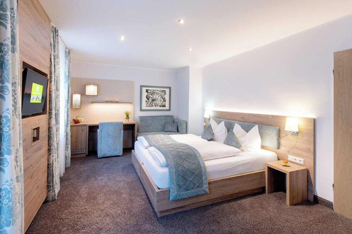 Ein modernes Hotelzimmer mit einem großen Bett, einem Schreibtisch und einem kleinen Tisch.