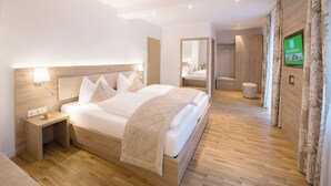 Ein modernes Hotelzimmer mit einem hölzernen Bett, einem Nachttisch, einem Fernseher und einem Spiegel.