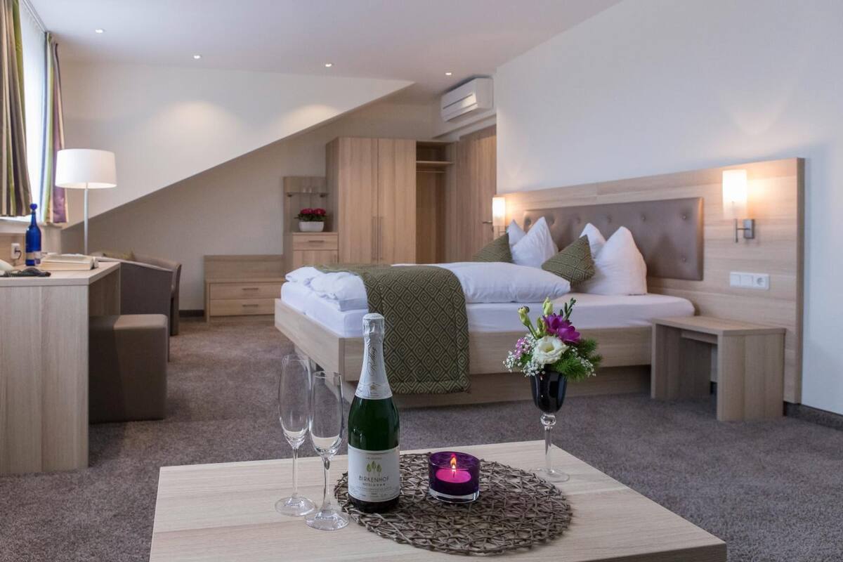 Ein Hotelzimmer mit Bett, Nachttisch, Lampe und einer Weinflasche.