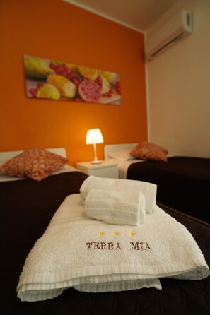 A hotel room with a bed, a nightstand, a lamp, and a painting on the wall. - Terra Mia Affittacamere (Melilli)