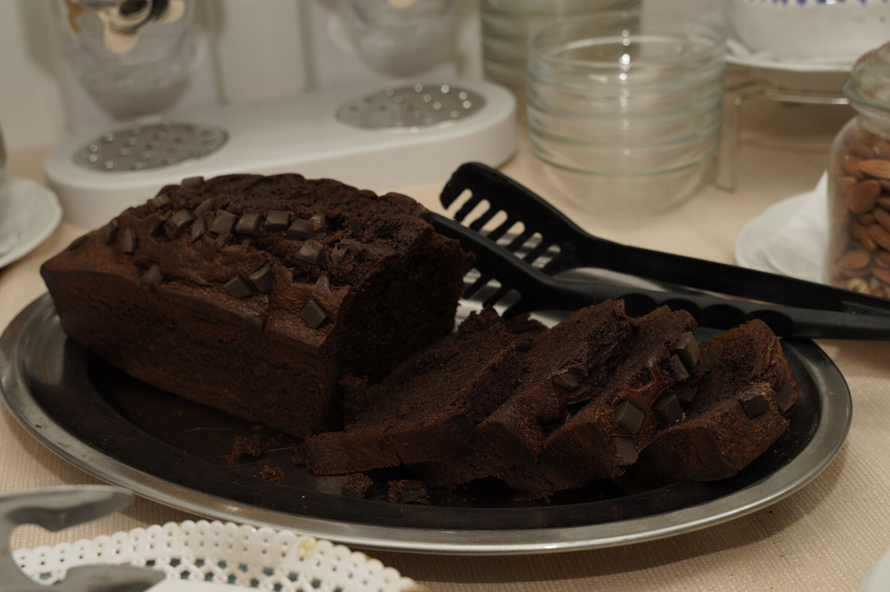 A chocolate cake on a plate with a spatula beside it.