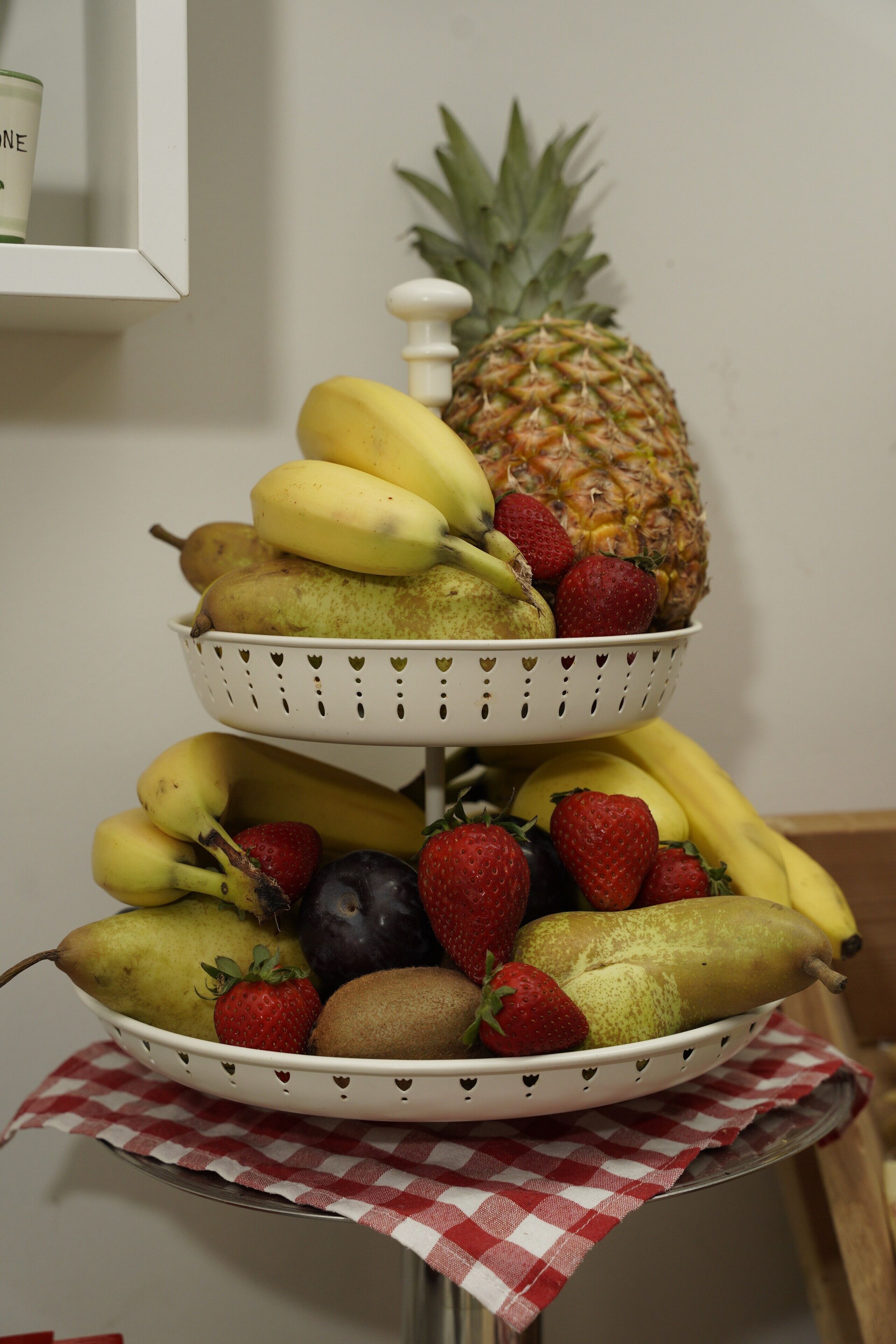 A fruit stand with bananas, strawberries, blueberries, and a pineapple.