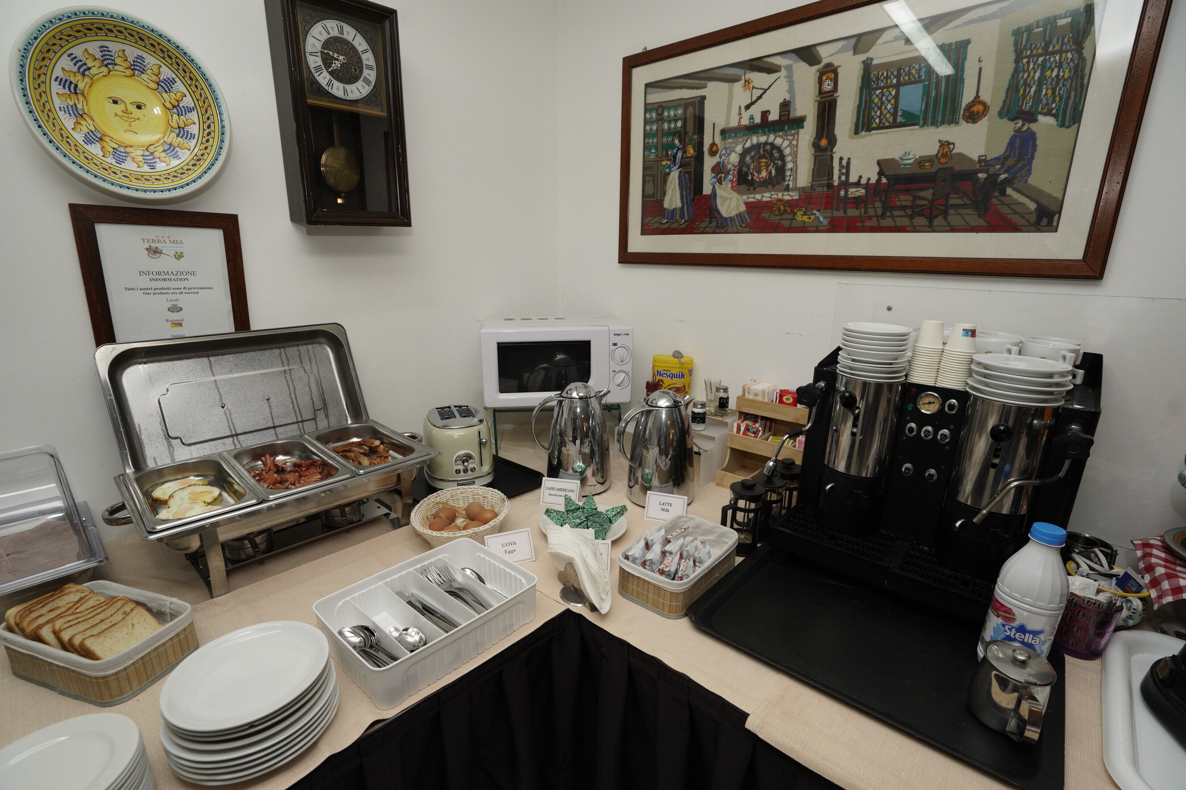 Un buffet de petit-déjeuner proposant une variété d’aliments, des machines à café et un tableau encadré accroché au mur.