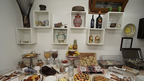 Una mesa de buffet con diversos alimentos y una exhibición de objetos decorativos en estantes.