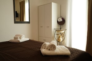 Quarto de hotel com uma cama, guarda-roupa, espelho e abajur.