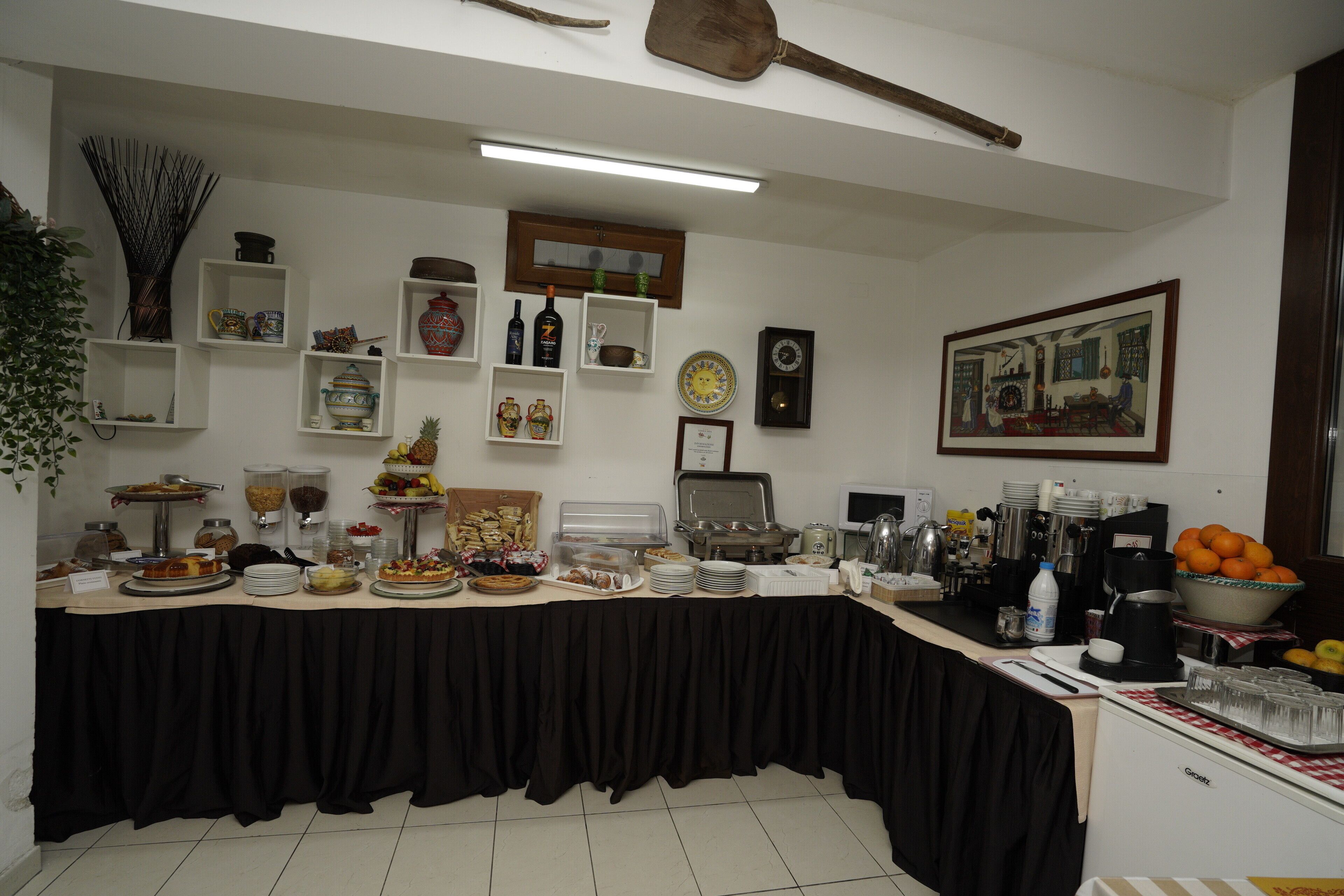 Una mesa de buffet con diversos alimentos, una estación de café y un reloj en la pared.