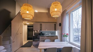 A modern kitchen with a dining area, featuring a staircase, a coffee machine, and a window with a view. - Spot Apartments Helsinki (Helsinki)