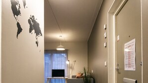 A hallway with a black carpet, a flat-screen TV, a potted plant, and a door with a notice on it. - Spot Apartments Helsinki (Helsinki)