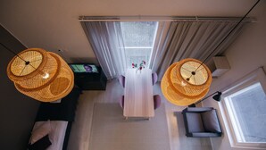 A modern living room with a central table, two wicker lamps, a sofa, and a window with curtains. - Spot Apartments Helsinki (Helsinki)