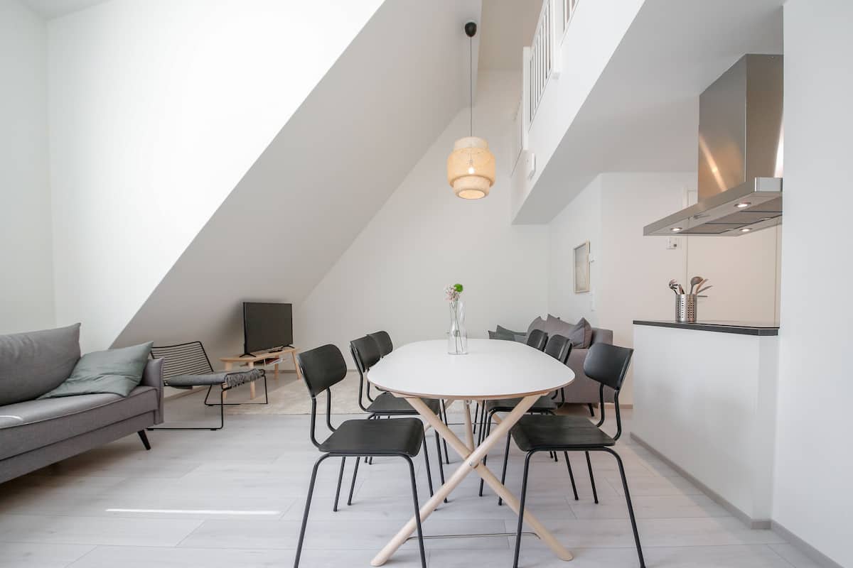 Un moderno loft con zona pranzo, divano, televisore e cucina.