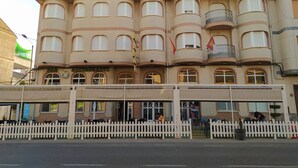 A hotel with a sign reading "HOTEL ARO'S". It features multiple balconies and a white picket fence in front. - Hotel Aros (Casas-Ibanez)
