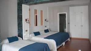A hotel room with two beds, a wardrobe, and a bathroom visible through an open door. - Hotel Aros (Casas-Ibanez)