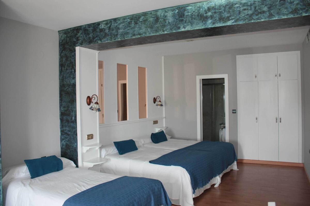 A hotel room with two beds, a wardrobe, and a bathroom visible through an open door.
