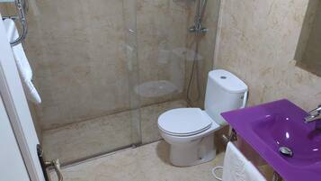 Un baño con cabina de ducha de vidrio, inodoro blanco y lavamanos morado.
