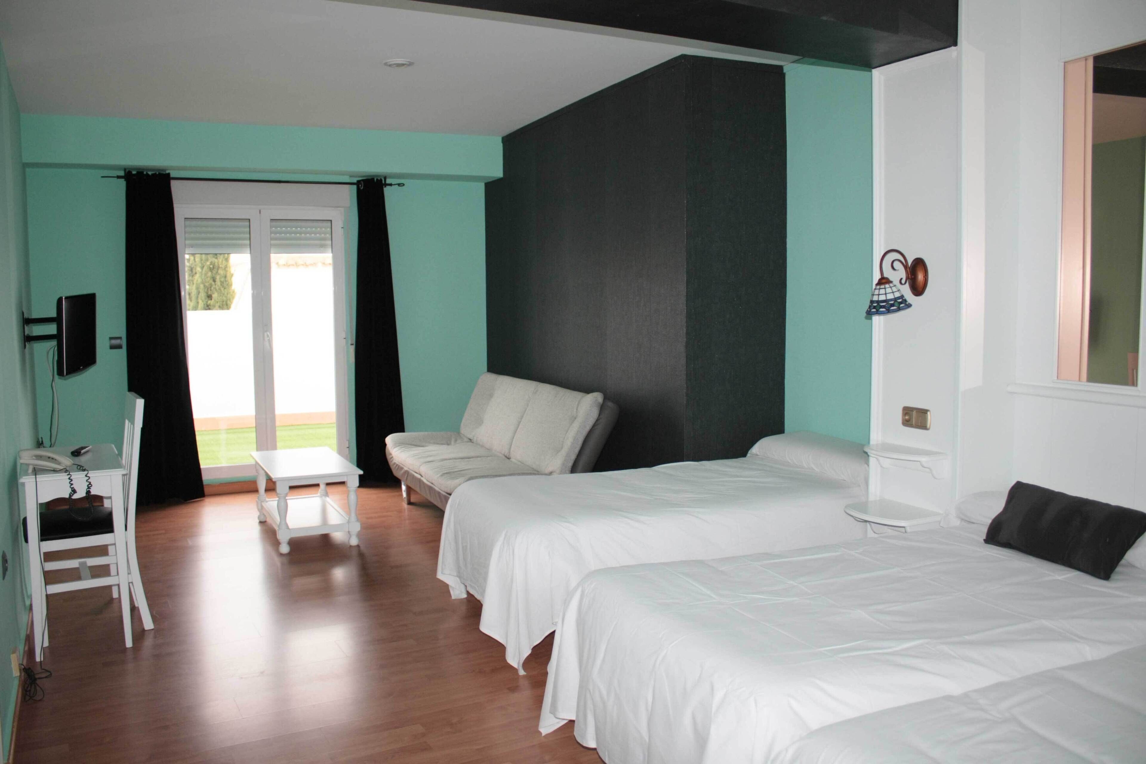 Habitación de hotel con dos camas, una mesita, una silla y un sofá.