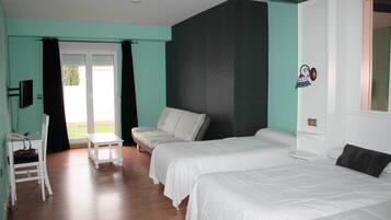 Habitación de hotel con dos camas, una mesita, una silla y un sofá.