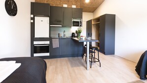 A compact kitchen with a refrigerator, microwave, and sink. There is a small dining area with stools and a table.