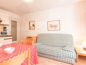 A compact living space with a kitchenette, a dining table with a polka-dotted tablecloth, a checkered sofa, and a framed picture on the wall. - 2-Room Apartment with Parking, Balcony, Sleeps 4 - Briançon (Briançon)