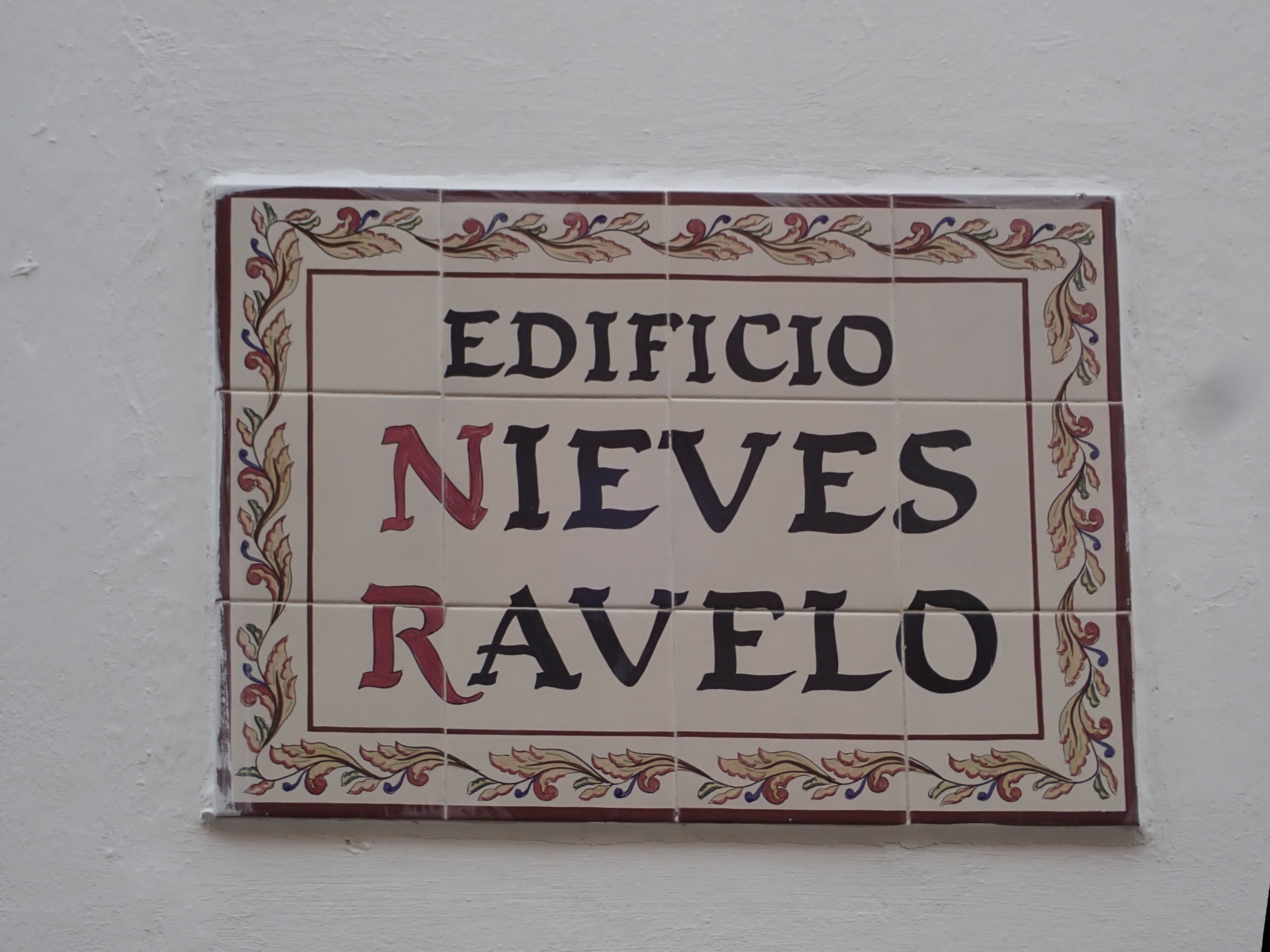 A tiled sign with the words "EDIFICIO NIEVES RAVELO" in a decorative border.