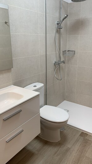 Un baño moderno con inodoro, lavabo y ducha.