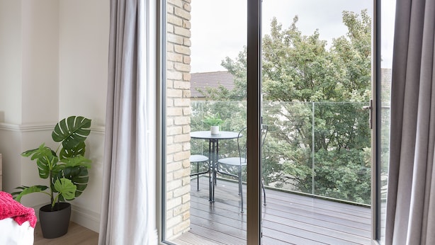 Ein Balkon mit einem Blumentopf, einem kleinen Tisch und Stühlen.