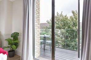 Ein Balkon mit einem Blumentopf, einem kleinen Tisch und Stühlen.