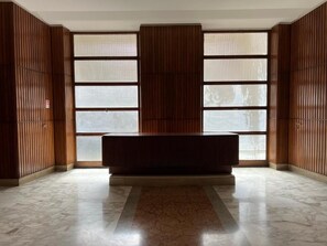 A room with a marble floor, a central dark-colored bench, and wooden paneling on the walls. - Affreschi Al Vaticano (Rome)