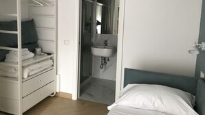 A bedroom with a bed, a walk-in closet with shelves and hangers, and a bathroom with a sink and mirror. - Affreschi Al Vaticano (Rome)