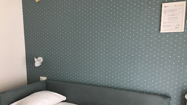 A single bed with a white duvet in a room with a polka dot wall pattern. - Affreschi Al Vaticano (Rome)