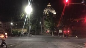 A nighttime street scene with a prominent building with a dome in the background. - Affreschi Al Vaticano (Rome)