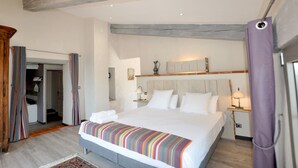 Un dormitorio con una cama grande, un armario de madera y un baño visible a través de una puerta abierta.