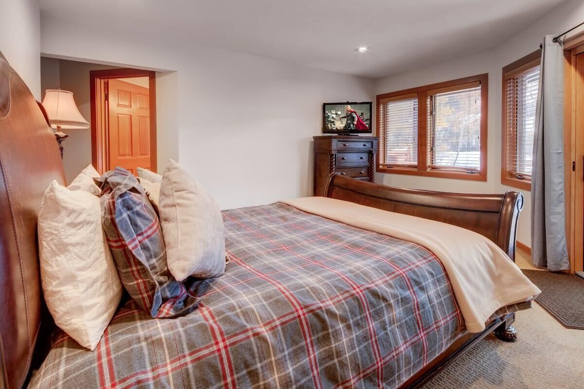 Een slaapkamer met een bed, een televisie, een houten dressoir en een deur.