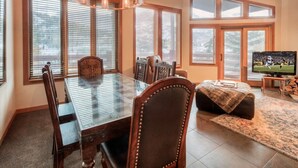 A dining area with a glass-top table, wooden chairs, and a chandelier. - Deer Valley Enclave - Spacious 2BR, Mountain Views (Park City)
