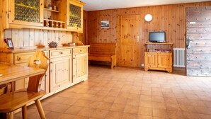 Een houten interieur met een eethoek, houten kasten, een televisie en een radiator.