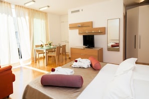 Relax in a stylish room with a comfortable bed, armchair, and dining table, featuring a flat-screen TV and large mirror.