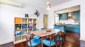 A modern kitchen with teal cabinets, a wooden dining table with blue chairs, and a built-in island with a sink. - 3 Funky &Cool Family Coolbinia 2BR for 4 (Coolbinia)