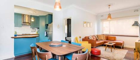 Eine moderne Küche mit Essbereich, ein Wohnzimmer mit Sofa und Couchtisch sowie ein großes Fenster für natürliches Licht.