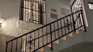 A staircase with black railings leading to a white building with barred windows and a sign reading "CASA PICO". - AP327 - Casa Pico (Nerja)