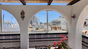A dining area with a view of a cityscape, featuring a table set with plates, glasses, and a bottle of wine. - AP327 - Casa Pico (Nerja)