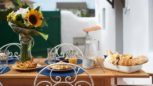 A breakfast table with croissants, a pitcher of orange juice, and a vase of flowers.
