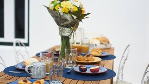 A breakfast table with a floral centerpiece, plates of food, and a mug.